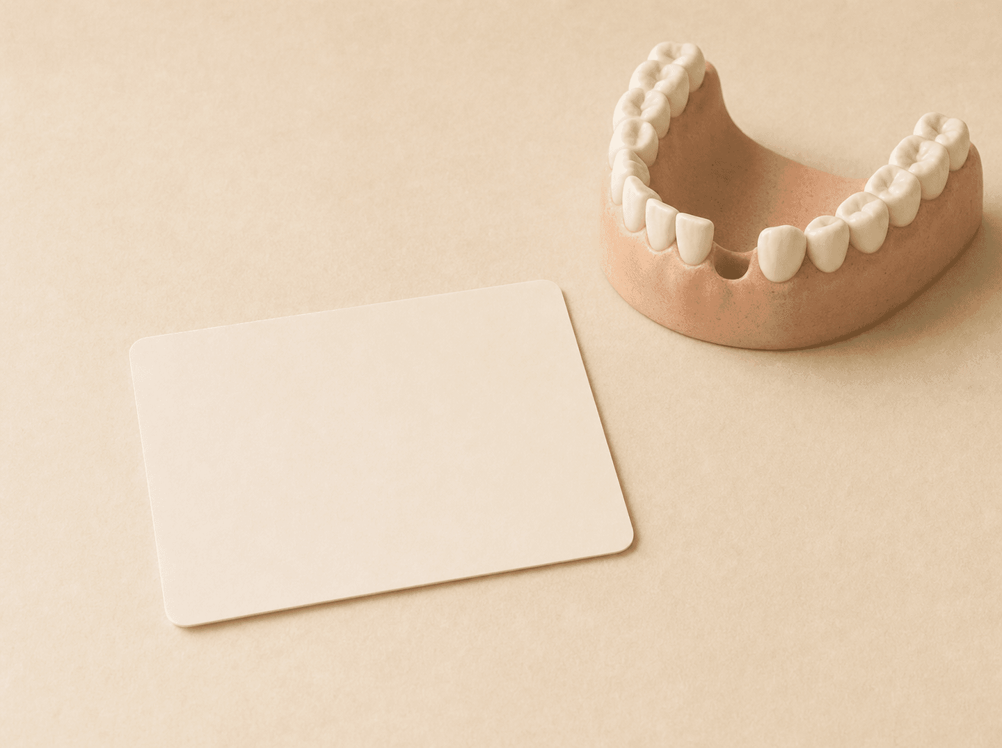 Editorial illustration of a plain blank card lying on a desk beside a simple rounded model of a lower row of teeth with one tooth absent, leaving a clear empty gap in the row (a tooth missing before dental coverage began), warm muted tones